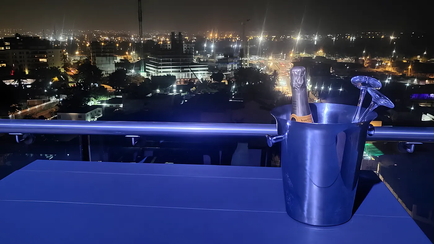 Seau à champagne et flûtes sur la balustrade, la ville de nuit en arrière-plan