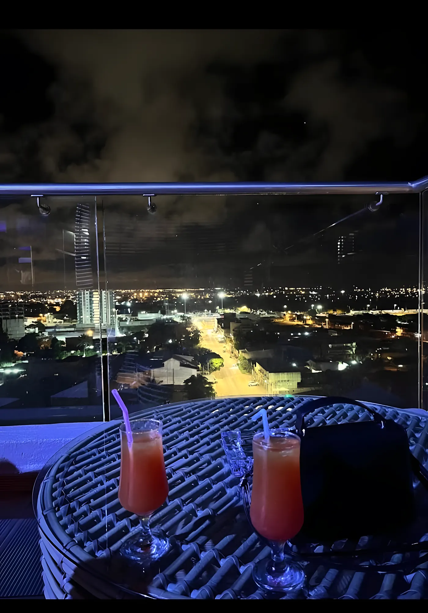 Deux cocktails sur une table de la terrasse, la ville illuminée en contrebas