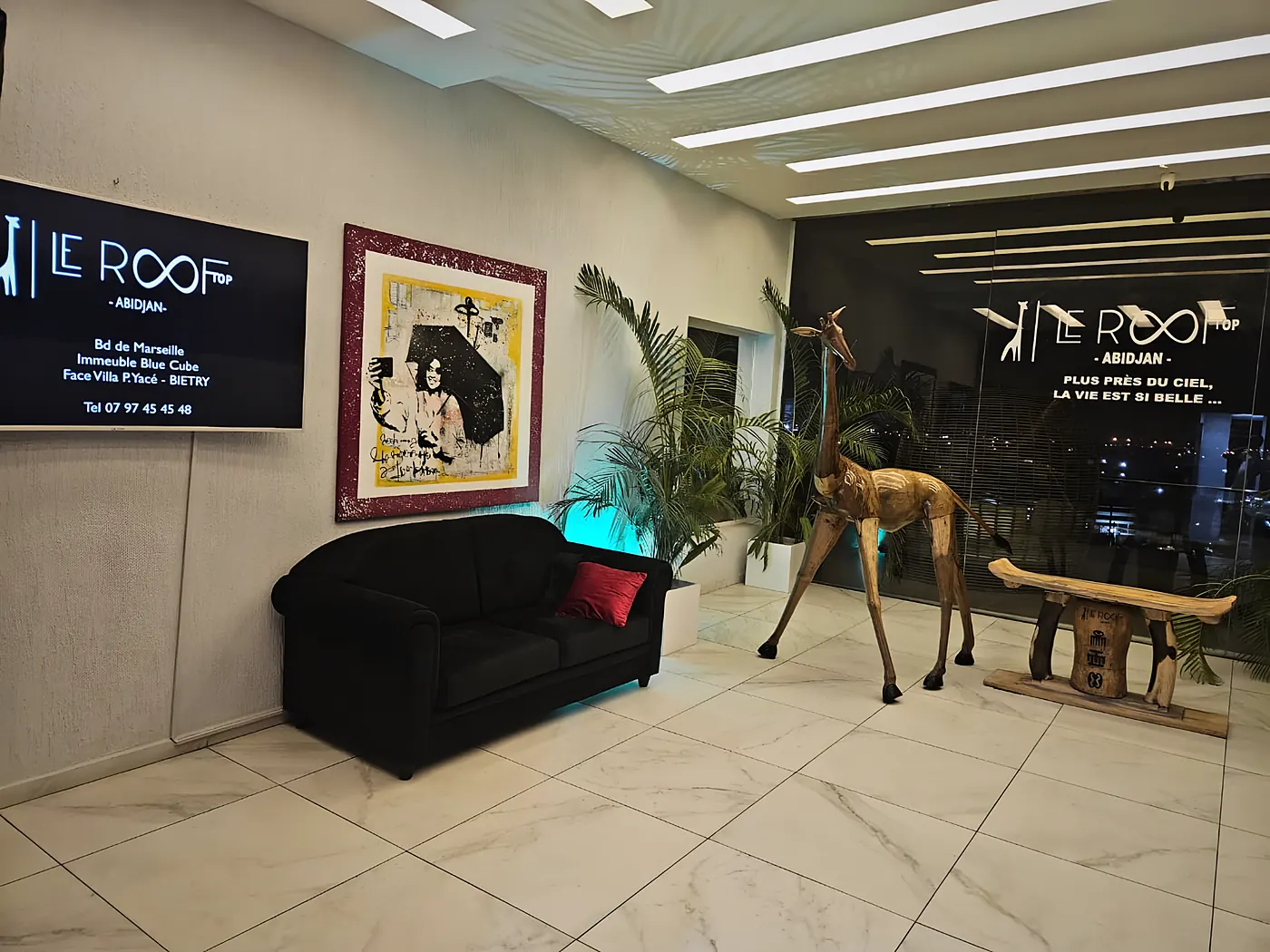 L'entrée du Rooftop, sa girafe sculptée et le logo sur la vitre