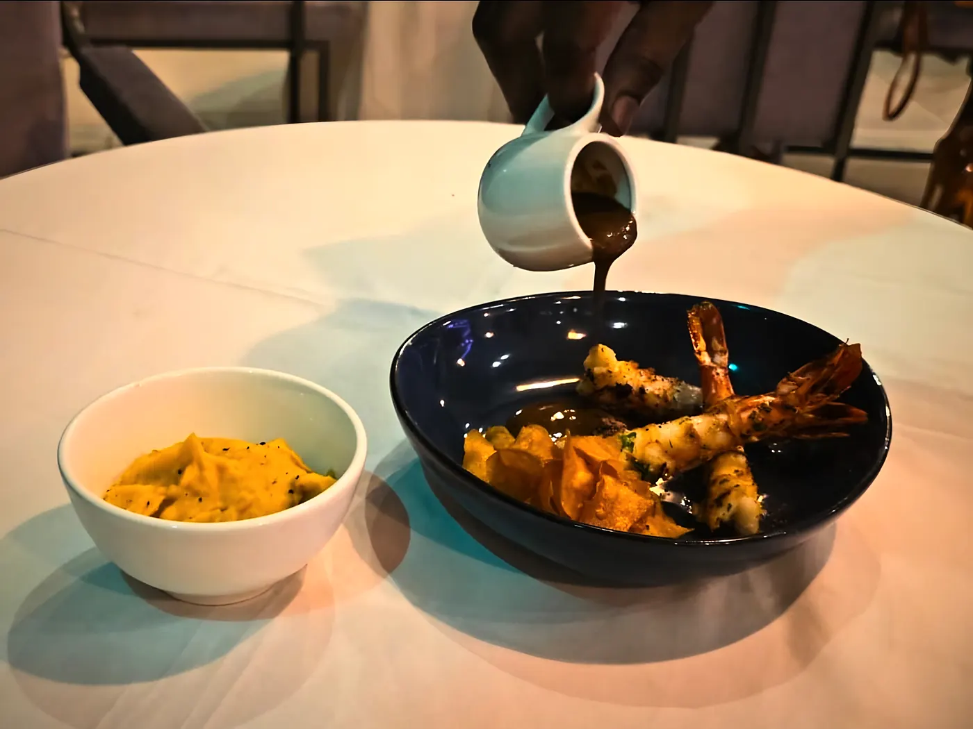 La bisque versée à table sur les gambas du golfe de Guinée