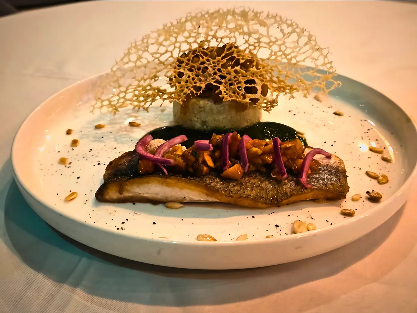 Poisson saisi sur sa peau, pickles d'oignon rouge, dentelle croustillante et condiment vert