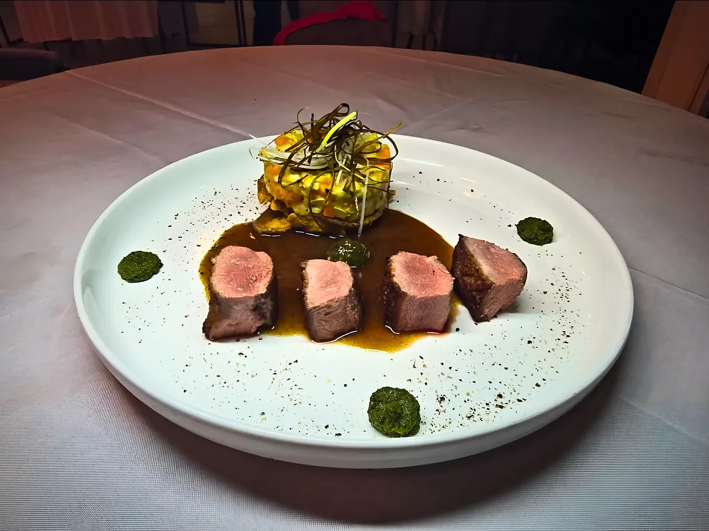Tranches de viande rosée, jus réduit et tartare de légumes, sur assiette blanche