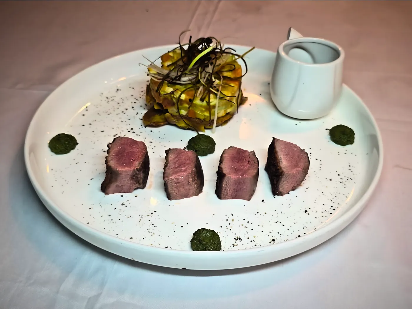 Tranches de viande rosée, tartare de légumes et pointes de condiment vert