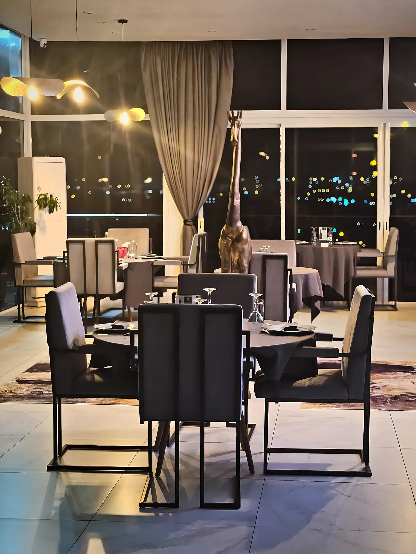 Tables dressées dans la salle vitrée, le soir